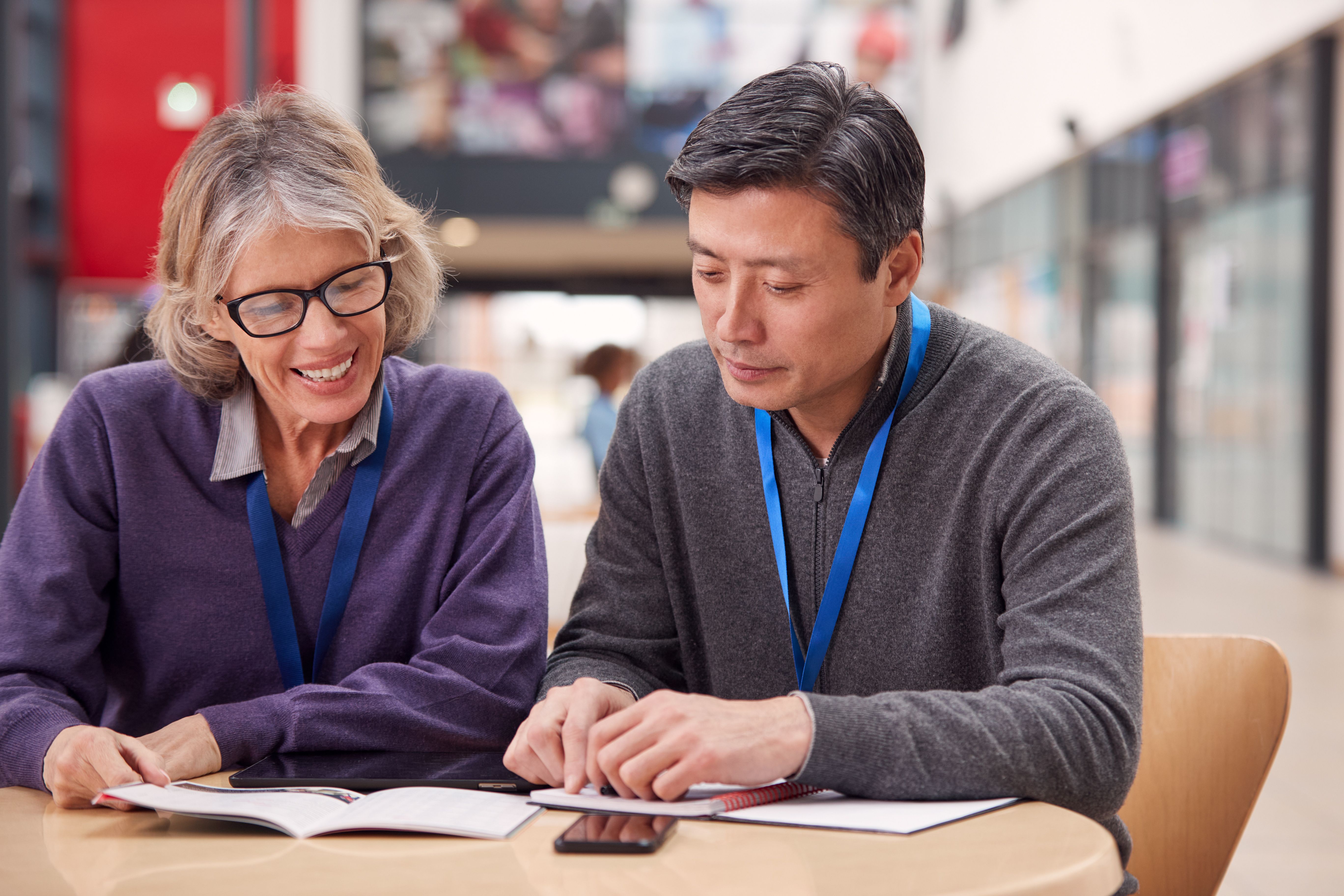 Two recreation staff with lanyards reviewing onboarding paperwork at a table