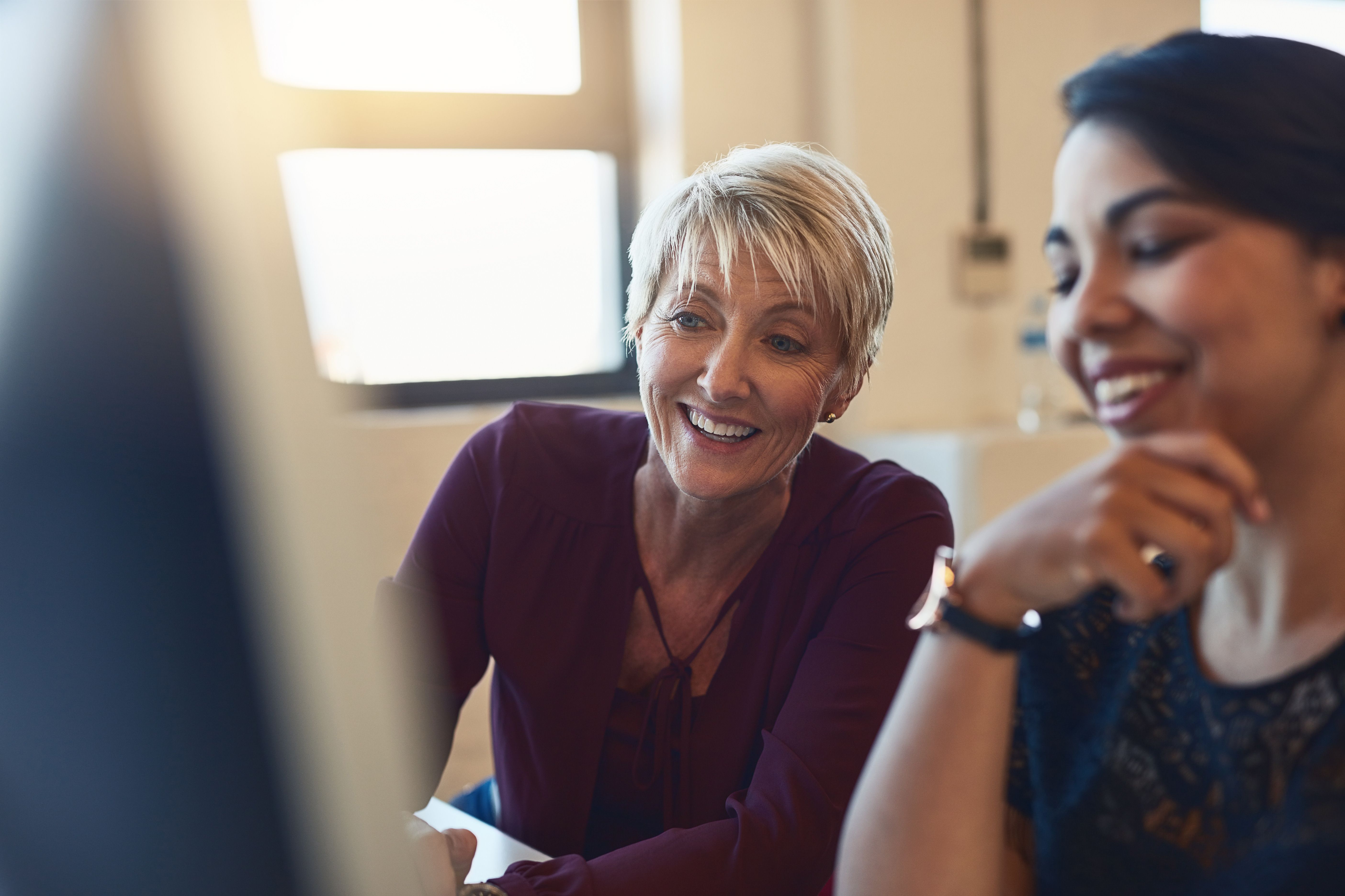 Two smiling team members looking at a computer screen together