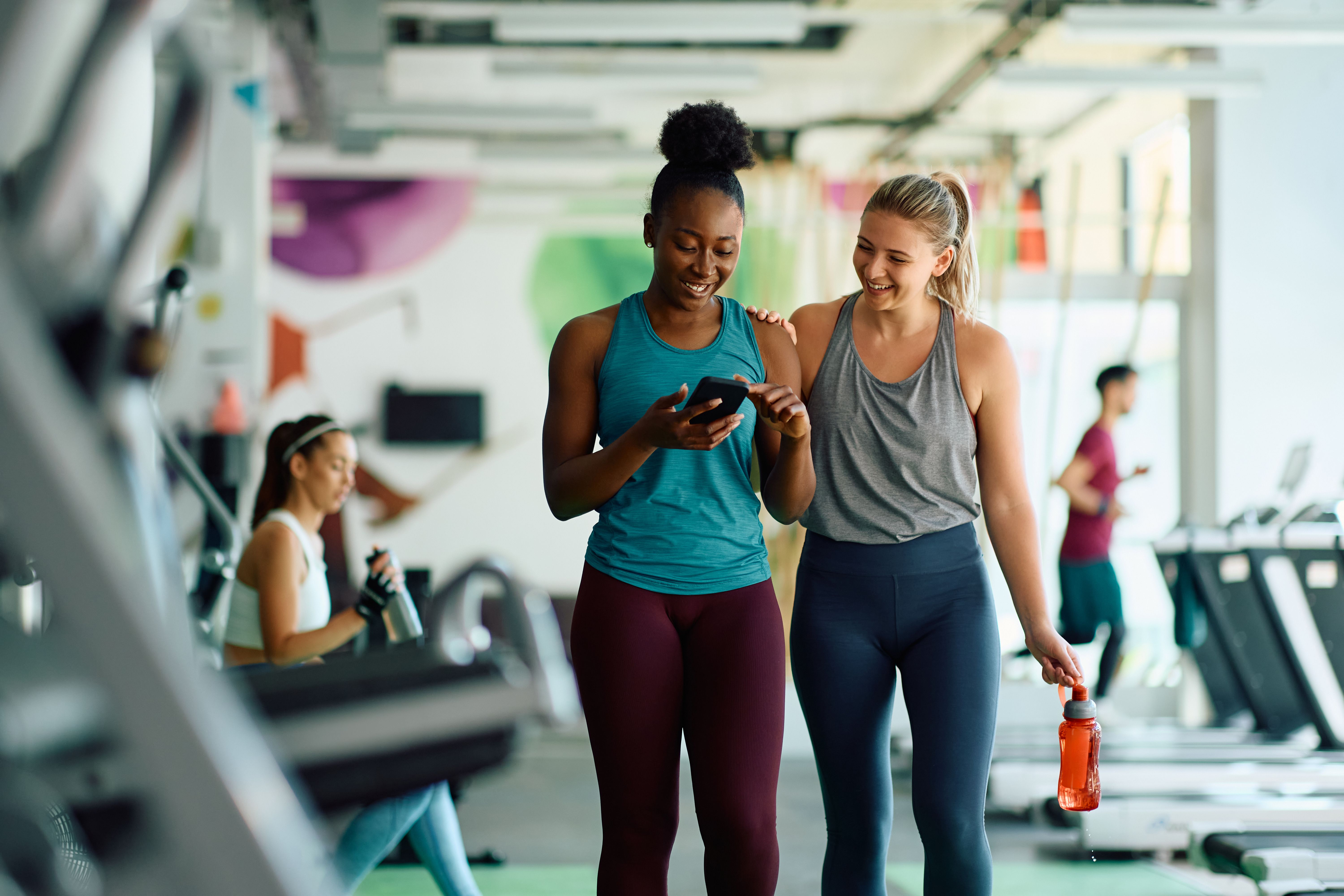 Two staff members reviewing a report together on a phone on the fitness floor of a community center